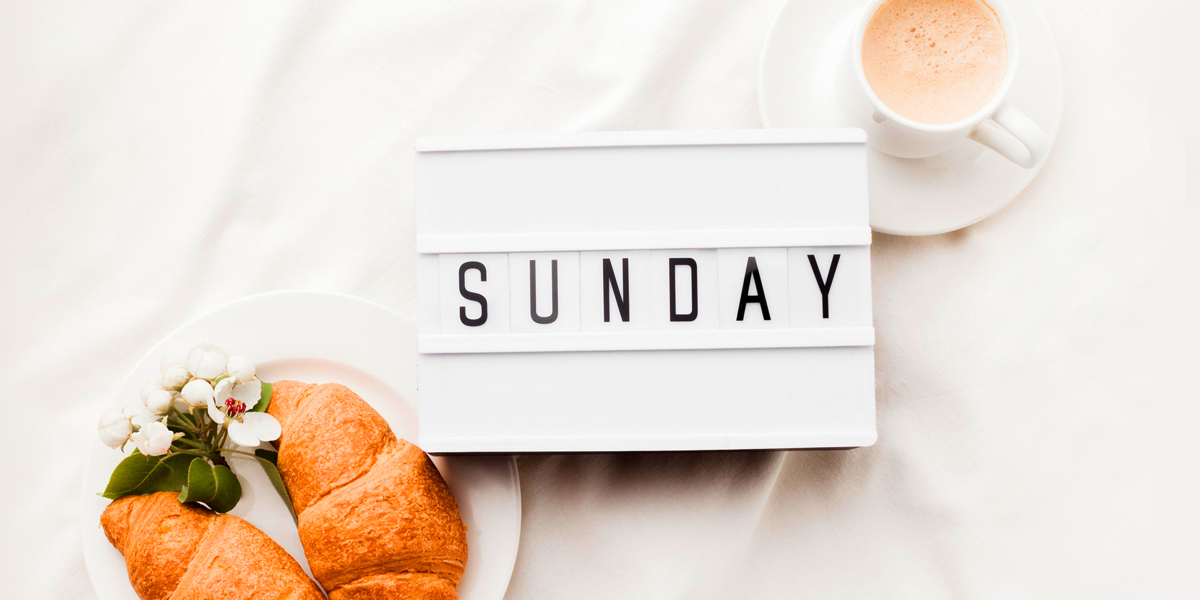 The word Sunday next to a cup of coffee and croissants | Source: Freepik