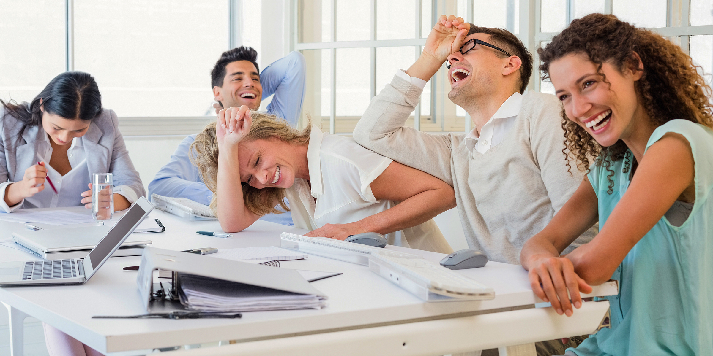 Office workers laughing during a meeting. | Source: Shutterstock